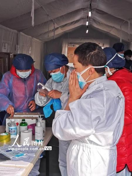 2月22日，武汉市东西湖武汉客厅方舱医院，一名护士正在进行进入方舱隔离病区的准备工作。轮班的医务人员必须在用帐篷搭建的隔离通道入口处进行仔细完备的装备穿戴，方可进入方舱隔离病区。（陈黎明 人民图片）