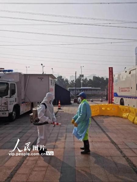 2月22日，武汉客厅方舱医院，工作人员正在进行日常的消毒程序，包括建筑表面、地面以及服装表面。（陈黎明 人民图片）